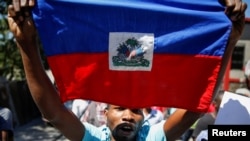 Yon manifestan lanse slogan pandan l pote drapo ayisyen an nan yon manifestasyon kont Prezidan Ayiti a 