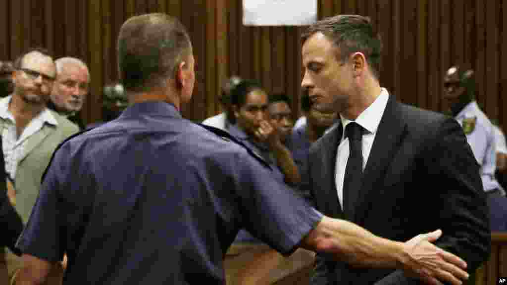 Oscar Pistorius, right, is led out of court in Pretoria, South Africa, Tuesday, Oct. 21, 2014.