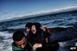 A man comforts a woman upon arrival with other refugees and migrants on the Greek island of Lesbos on October 25, 2015 after they crossed the Aegean sea from Turkey.