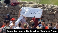 In this undated photo published by the U.S.-based Center for Human Rights in Iran, Iranian Azerbaijanis stage an annual July protest against discrimination targeting their community at Babak Fort in East Azerbaijan province. The slogan on the white banner calls for the release of a detained Azeri rights activist, Siamak Mirzaei.