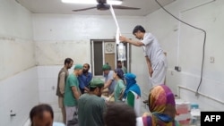 FILE - In this photograph released by Medecins Sans Frontieres (MSF) on Oct. 3, 2015, surgeons work in an undamaged part of the MSF hospital in Kunduz after the operating theaters were destroyed in an airstrike.