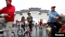 People cycle their bicycles at the Chiang Kai-shek Memorial Hall in Taipei December 31, 2011.