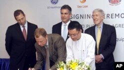 President and CEO of General Electric ASEAN, Stuart Dean, second from left, signs documents during the signing ceremony between Sea Lion Co. Ltd., General Electric Healthcare and Bahosi and Pun Hlaing Hospitals in Rangoon, Burma, July. 14, 2012. 