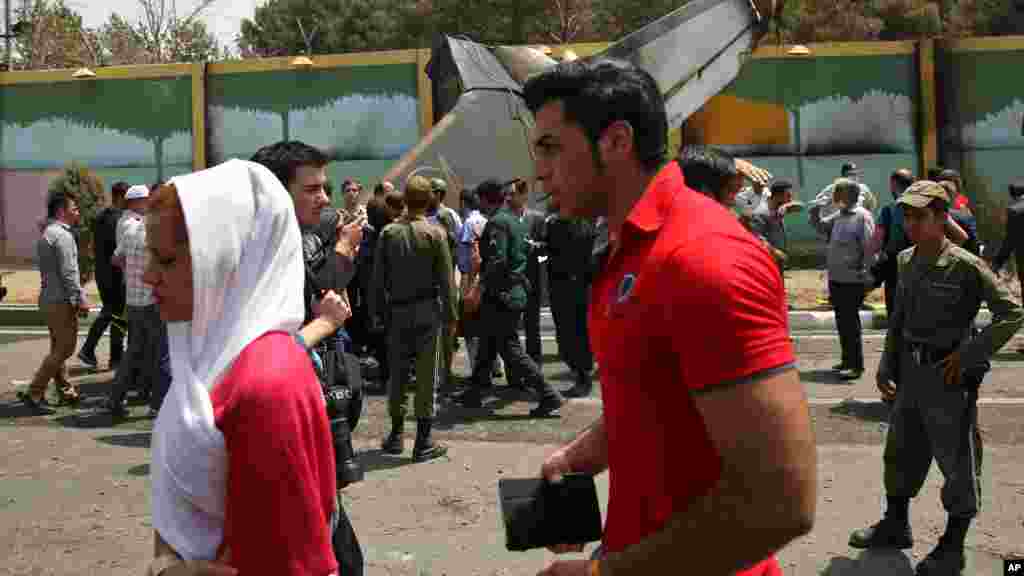 Iranians walk past the site of a passenger plane crash near the capital Tehran, Iran, Aug. 10, 2014.