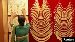 A saleswoman arranges a gold necklace inside a jewellery showroom in the southern Indian city of Kochi, April 16, 2013. 