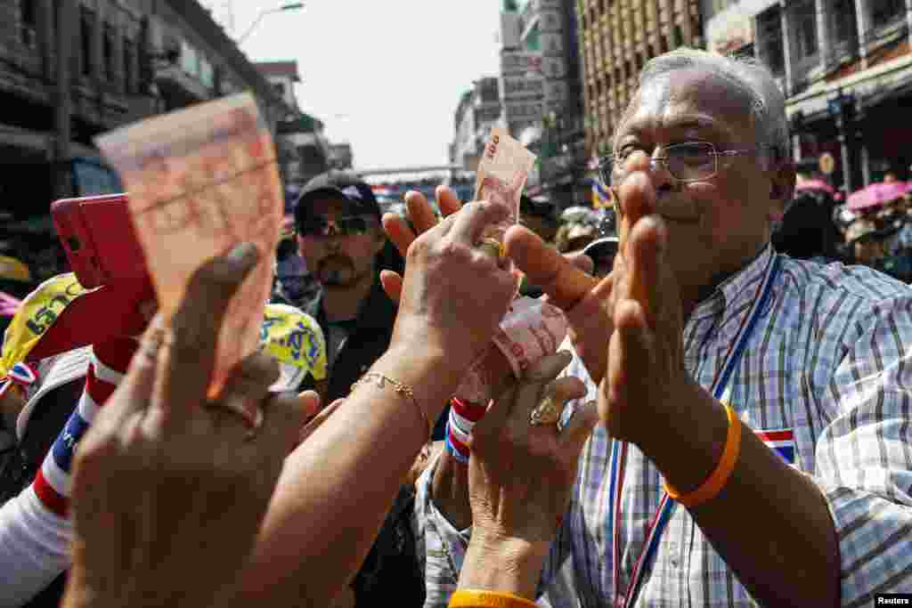 Anti-government protest leader Suthep Thaugsuban (R) receives a donation from his supporters as he marches during a rally, Bangkok, Thailand, January 5, 2014. 