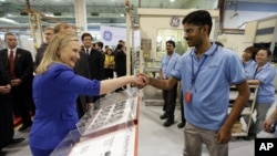 U.S. Secretary of State Hillary Rodham Clinton, left, shakes hands with a worker during her visit to a General Electric aviation facility in Singapore Saturday, Nov. 17, 2012.