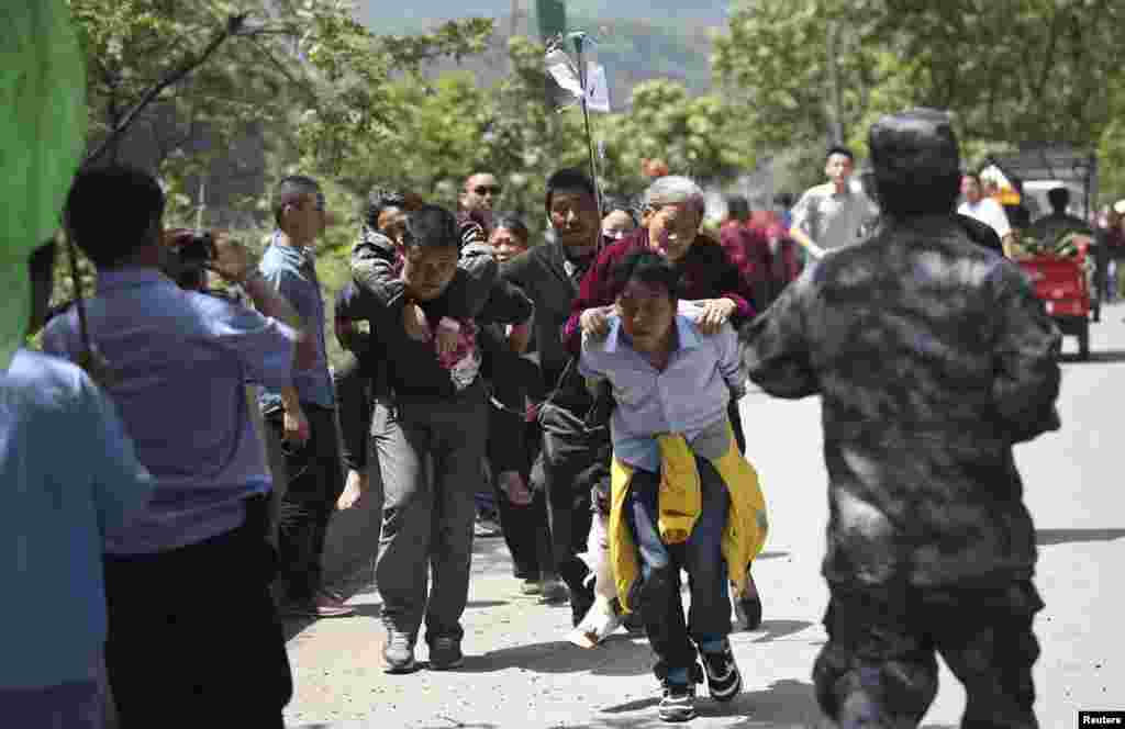 Men carry injured people to an ambulance at Longmen Village, Lushan county, Ya&#39;an, Sichuan province, Apr. 20, 2013.