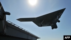 An X-47B unmanned combat air system (UCAS drone) demonstrates touch and go landing on the flight deck of the aircraft carrier USS George H.W. Bush in the Atlantic Ocean, May 17, 2013.