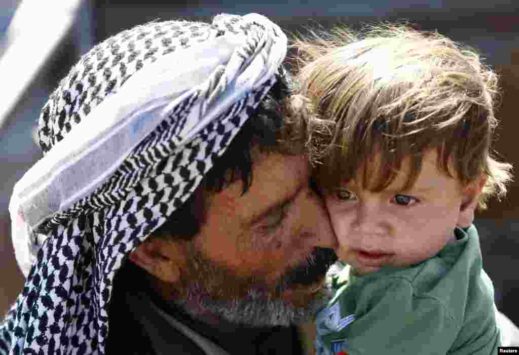 A Kurdish Syrian refugee carries an infant after crossing the Turkish-Syrian border near the southeastern town of Suruc in Sanliurfa province. Nearly 140,000 Syrian Kurds have fled into Turkey since last week, the fastest exodus of the entire three-year civil war.