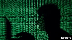 Seorang pria sedang bekerja dengan laptop dengan latar kode-kode siber dalam foto ilustrasi, 13 Mei 2017.
