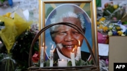 FILE - Candles are seen burning by a portrait of Nelson Mandela outside of the Mediclinic Heart Hospital in Pretoria, South Africa, where he was in critical condition, July 6, 2013. 