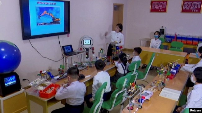 North Korean students learn and engage with a robot in Pyongyang, North Korea November 3, 2021, in this still image obtained from Reuters. (REUTERS TV/KRT)