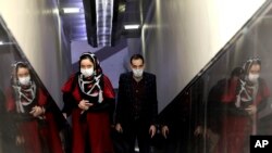 People wear masks to help guard against the Coronavirus as they ride an escalator at a the metro station, in Tehran, Iran, Sunday, Feb. 23, 2020. 