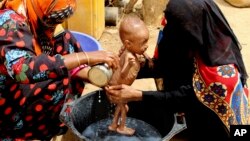 FILE - A severely malnourished infant is bathed in a bucket in Aslam, Hajjah, Yemen, Aug. 25, 2018.