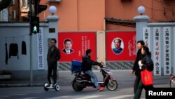 上海市民在张贴着中共领导人习近平和前领导人毛泽东的宣传画前走过。(资料照片)