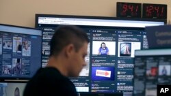 Un hombre trabaja en su escritorio frente a los monitores durante una presentación en una sala especial donde Facebook monitorea el contenido relacionado con las elecciones en la plataforma.