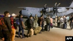 French and Afghan nationals line up to board a French military transport plane at the Kabul airport on August 17, 2021, for evacuation from Afghanistan after the Taliban's stunning military takeover of the country.
