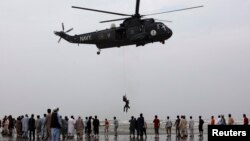 31일 파키스탄 남부 카라치 해변에서 구조대가 헬리콥터로 익사자를 건져올리고 있다.