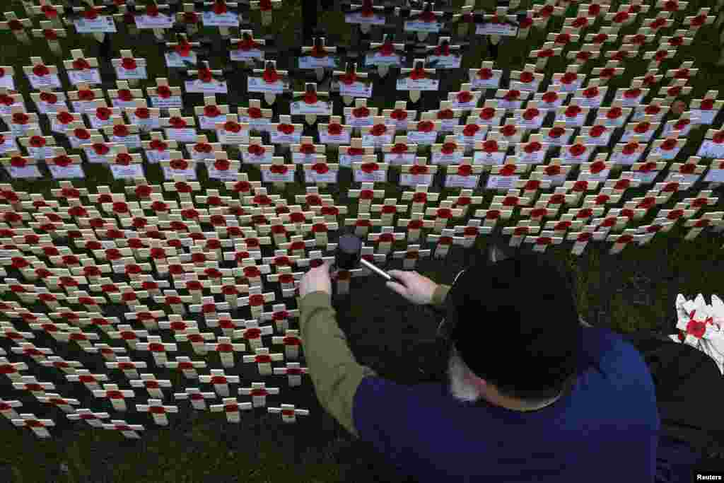 A volunteer plants crosses decorated with poppies in the lawn outside Westminster Abbey in central London, Britain.