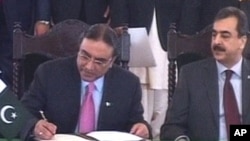 Pakistan's President Asif Ali Zardari, left, signs a constitutional reforms law as Prime Minister Yousuf Raza Gilani looks on during a ceremony in Islamabad, 19 Apr 2010