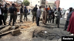 Security officials assess the scene of a suspected Boko Haram bomb attack that killed four people in Nigeria's northern city of Kaduna, April 8, 2012. 