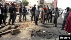 Security officials assess the scene of a bomb blast that killed four people by suspected members of Nigerian Islamist sect Boko Haram in Nigeria's northern city of Kaduna, April 8, 2012.