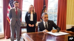 FILE - President Barack Obama signs an Executive Order, entitled “Planning for Sustainability in the Next Decade,” which will cut the Federal Government’s greenhouse gas (GHG) emissions over the next decade, March 19, 2015. Behind the president is Senior Adviser Brian Deese and Kate Brandt, Federal Chief Sustainability Officer. 