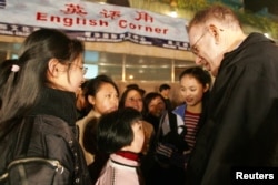 资料照片: 2005年3月25日，上海，年轻的中国学生在露天英语角与外国人练习英语。