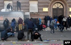 Albanian opposition supporters cover their faces after police threw tear gas during a protest outside the government building in Tirana, Feb. 16, 2019, demanding the resignation of the Albanian prime minister.