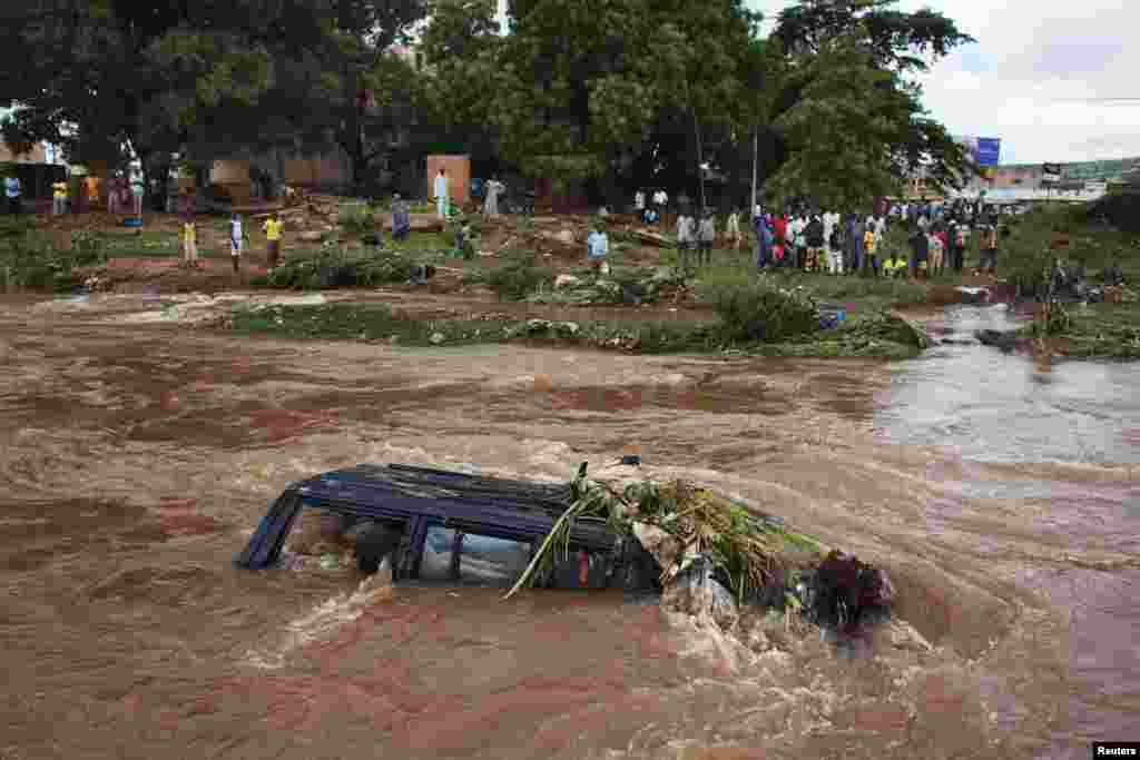 People look at a SUV submerged in floodwaters in Bamako, Mali. Torrential rains provoked flash floods, washing away homes in several neighbourhoods, a government minister said.