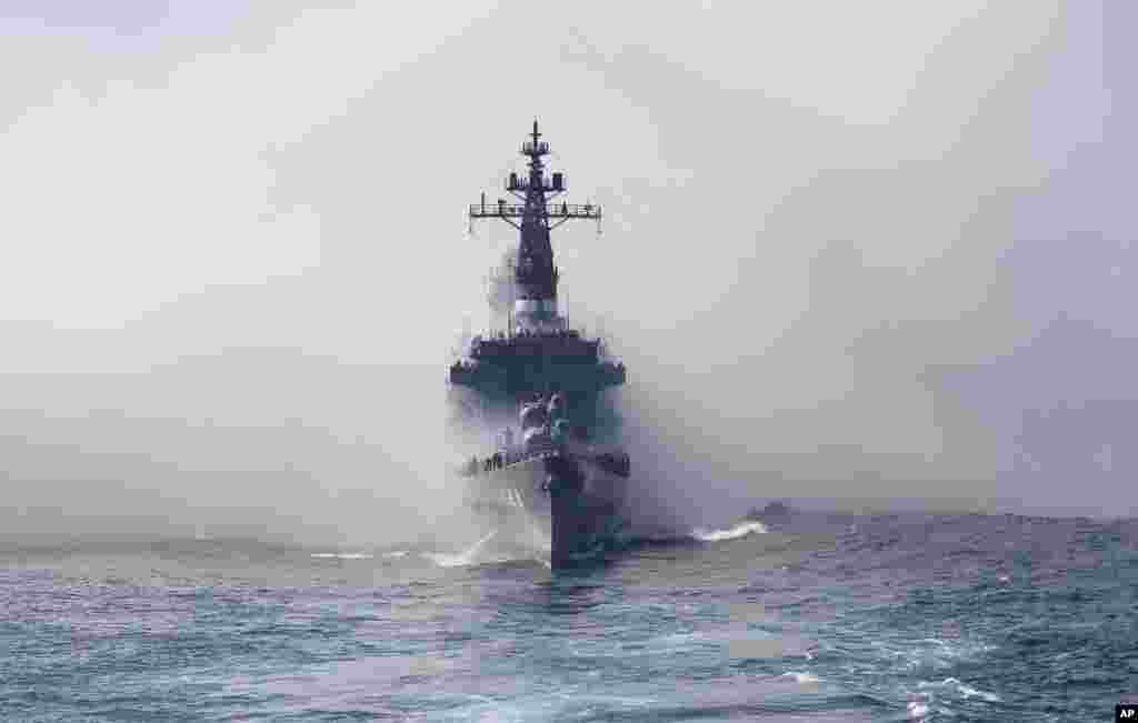 Japan Maritime Self-Defense Force escort ship Kurama appears from the smoke during a fleet review in the waters off Sagami Bay, south of Tokyo, Japan.