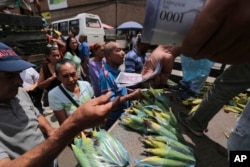 Customers pay with new bank notes for their groceries, at a market in Caracas, Venezuela, Sept. 23, 2017.