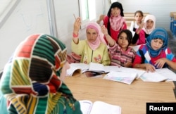 FILE - Syrian refugee children attend a class during the opening of a new school at the Al Zaatri refugee camp in the Jordanian city of Mafraq, near the border with Syria, June 4, 2013.