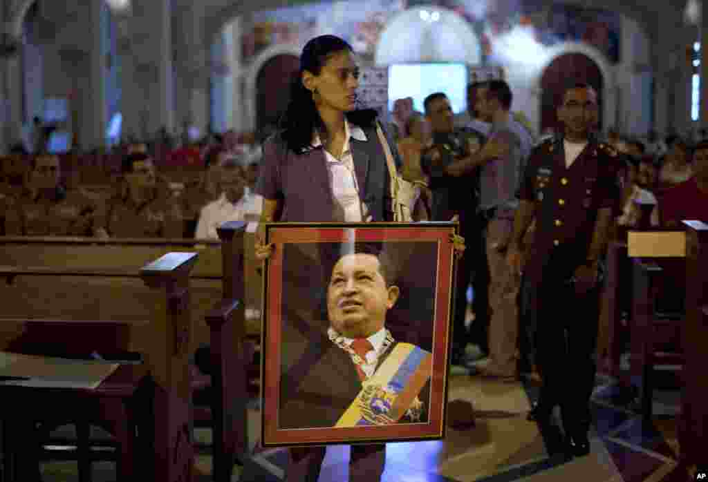 A woman carries an image of Venezuela's President Hugo Chavez before a mass in support of him in Havana, Cuba, December 13, 2012. 