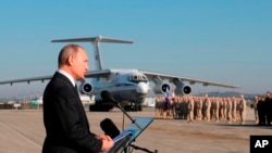 FILE - Russian President Vladimir Putin addresses troops at the Hemeimeem air base in Syria, Dec. 12, 2017. 