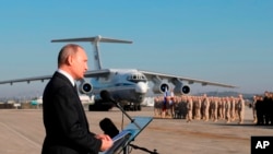 FILE - Russian President Vladimir Putin addresses the troops at the Hemeimeem air base in Syria, Dec. 12, 2017. U.S. President Donald Trump recently shocked advisers in declaring an intention to withdraw troops from Syria. Now, apparently angered by a suspected chemical attack, Trump is threatening imminent military strikes against the Syrian government forces he blames and rattling a saber at Syria’s patron, Russia.