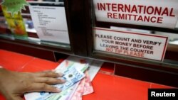 Uang Peso Filipina yang dikirim oleh tenaga kerja Filipina di luar negeri diterima oleh kerabatnya di pusat remitansi di Makati City, Metro Manila, Filipina, 19 September 2018.