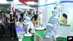 In this image taken from video, visitors look at iPal robots during the Shanghai CES electronic show in Shanghai, China, June 8, 2017. More than 50 companies are showcasing a new generation of robots at this week's Shanghai CES electronics show, most of which serve as companions at home, or butlers in shopping malls. 