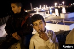 FILE - Mohamed, a Moroccan youth, smokes a cigarette near Melilla's harbor in Spain's north African enclave, Dec. 8, 2013.