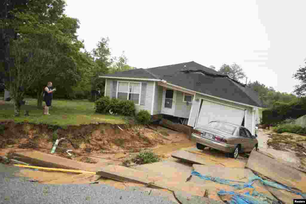 Rob Jernigan takes a photo of a friends house in the Springdale Forest Subdivision in Pensacola, Florida, April 30, 2014. A state of emergency was declared in Pensacola&#39;s Escambia County where emergency officials fought to save motorists stranded by flood waters.