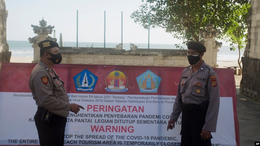Cảnh sát Indonesia canh gác lối vào một bãi biển bị phong tỏa tại Bali.