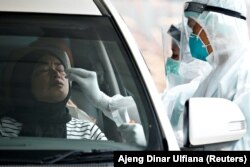 Seorang petugas kesehatan mengambil sampel tes usap COVID-19 di salah satu lokasi tes COVID-19 drive-through di Jakarta, pada 16 Desember 2021. (Foto: Reuters/Ajeng Dinar Ulfiana)