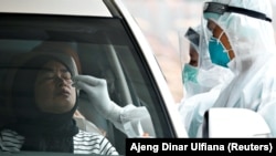 Seorang petugas kesehatan mengambil sampel tes usap COVID-19 di salah satu lokasi tes COVID-19 drive-through di Jakarta, pada 16 Desember 2021. (Foto: Reuters/Ajeng Dinar Ulfiana)