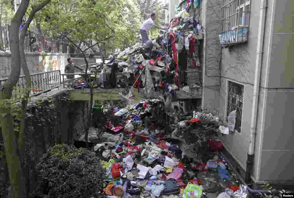 A pile of garbage is seen blocking an entrance to a residential building as workers clean up one of its apartments, in Qingdao, Shandong province, China, Sept. 9, 2015. According to local media, authorities have started cleaning out the apartment of an elderly woman, with the help of her son. The authorities were acting on persistent complaints from the surrounding residents due to the woman&#39;s collection and storage of trash in her home.
