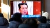 Ljudi gledaju TV program i fotografiju severnokorejskog idera Kim Džong Una, na železničkoj stanici u Seulu, Južna Koreja, 1. januara 2022.
