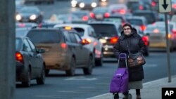 A woman waits for a bus at a bus stop in Moscow, Russia, Tuesday, Dec. 29, 2015. (AP Photo/Alexander Zemlianichenko)