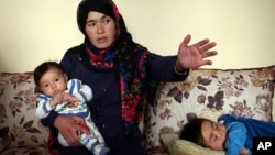 Jahantab Ahmadi, 25, holding her three month-old daughter Khezran, speaks during an interview with the Associated Press in Kabul, March 26, 2018.