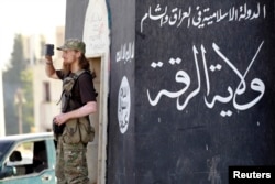 ນັກລົບຫົວຮຸນແຮງ ໃຊ້ໂທລະສັບມືຖື ບັນທຶກພາບ ຂອງພວກເພື່ອນນັກລົບ ເຂົ້າຮ່ວມ ໃນການເດີນສວນສະໜາມ ຢູ່ຕາມທ້ອງຖະໜົນ ຂອງແຂວງ Raqqa ທາງພາກເໜືອຂອງຊີເຣຍ, ວັນທີ 30 ມິຖຸນາ 2014.