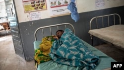 Une Mozambicaine est allongée sur un lit d'hôpital avec son nouveau-né dans la maternité Murrupelane de Nacala, dans la province de Nampula, au Mozambique, le 5 juillet 2018.
